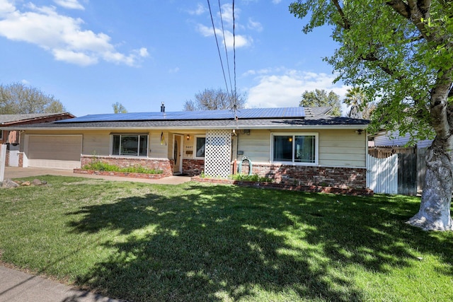 ranch-style home with a front yard, brick siding, a garage, fence, and roof mounted solar panels
