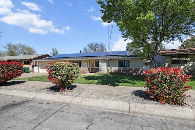 ranch-style house with a front yard, stone siding, an attached garage, and roof mounted solar panels