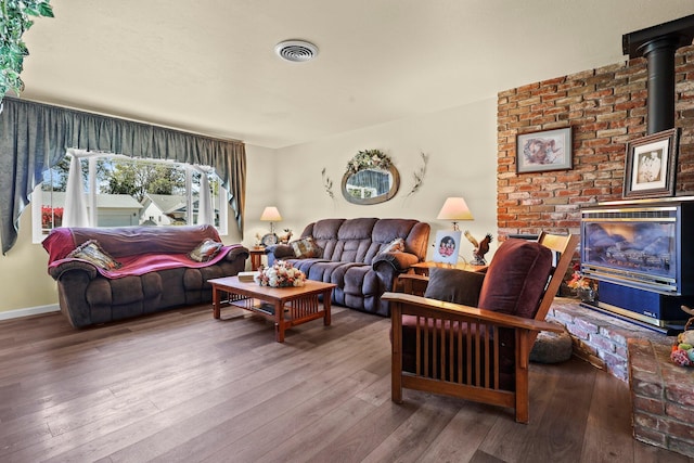 living area featuring a wood stove, wood-type flooring, and visible vents