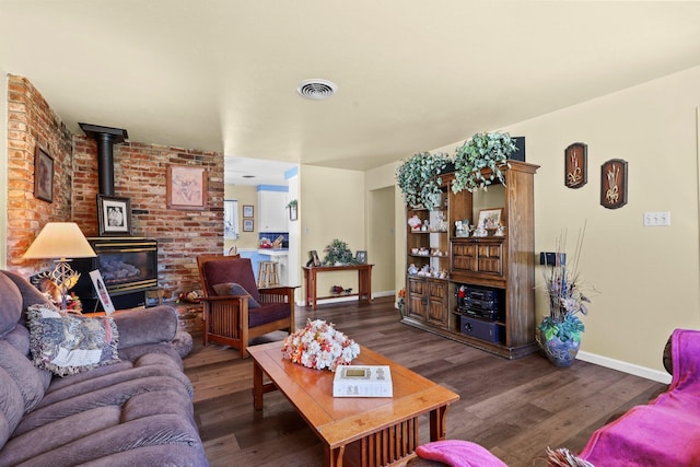 living room featuring a wood stove, visible vents, baseboards, and wood finished floors