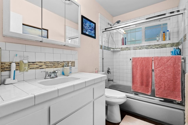 bathroom with shower / bath combination with glass door, vanity, backsplash, and toilet