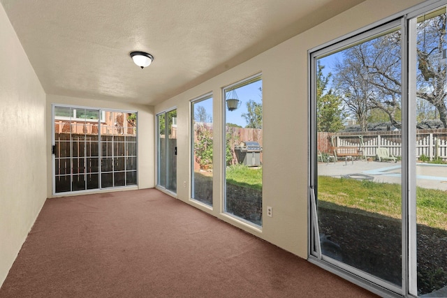 unfurnished sunroom with carpet and a textured ceiling