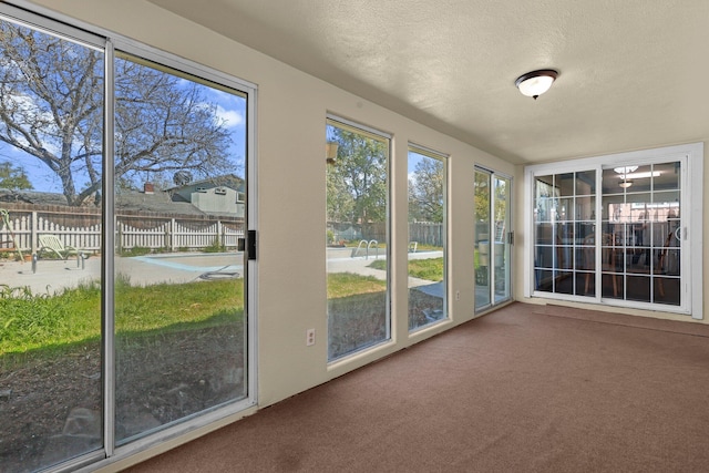 unfurnished sunroom with a textured ceiling and carpet floors
