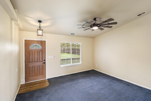 foyer featuring baseboards, ceiling fan, visible vents, and dark colored carpet