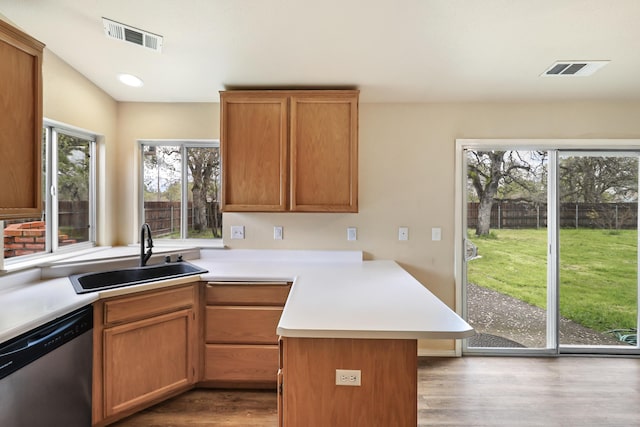 kitchen featuring light countertops, a sink, a peninsula, stainless steel dishwasher, and visible vents