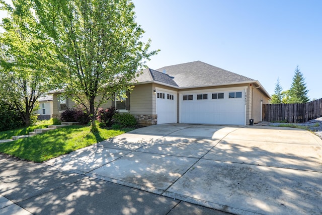 ranch-style home featuring fence, a front yard, stone siding, concrete driveway, and an attached garage