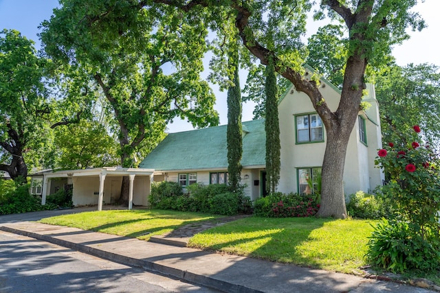 townhome / multi-family property featuring stucco siding, aphalt driveway, a front lawn, and an attached carport