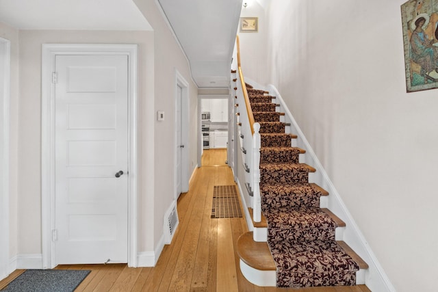 stairway featuring hardwood / wood-style floors, baseboards, and visible vents