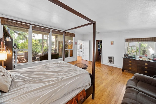 bedroom with a walk in closet, baseboards, and wood finished floors