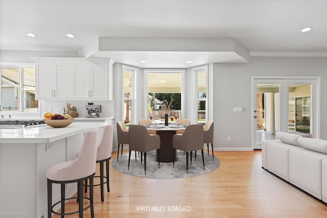 dining space featuring light wood-style flooring, recessed lighting, crown molding, and baseboards