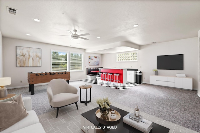 carpeted living area featuring wet bar, ceiling fan, baseboards, and recessed lighting