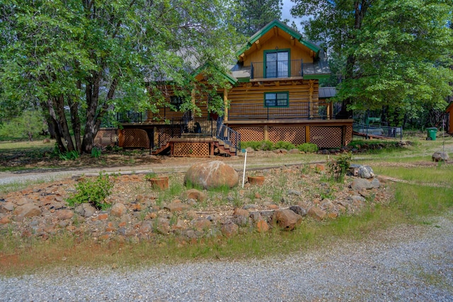 rear view of property with log siding, a wooden deck, stairway, and a balcony