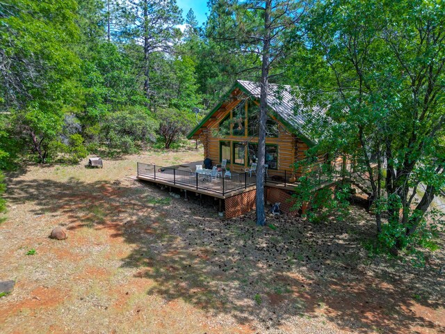 back of property with a deck, a view of trees, and log siding
