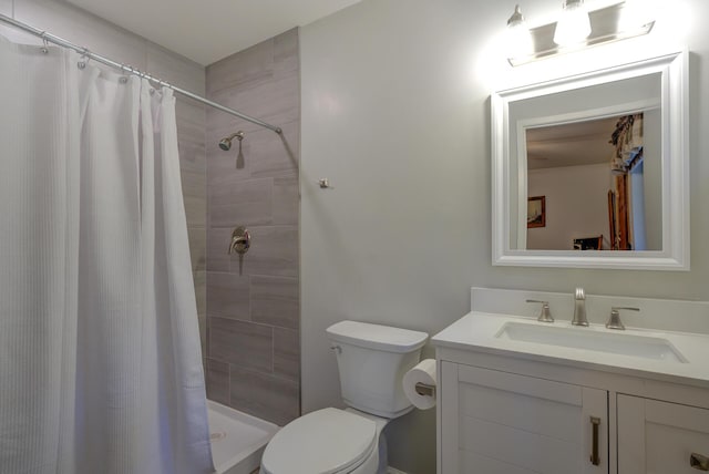 bathroom with vanity, toilet, and a tile shower