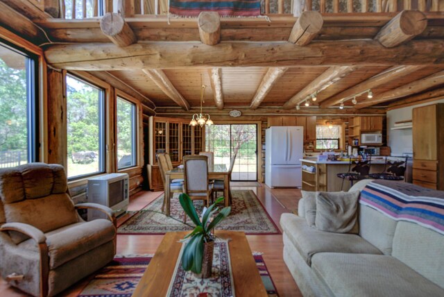 living room with light wood finished floors, beam ceiling, log walls, wooden ceiling, and a chandelier