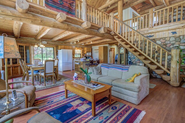 living room featuring beamed ceiling, a chandelier, light wood-type flooring, and wooden ceiling