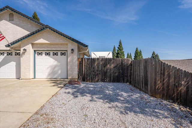 2919 Buckingham Dr, Shasta Lake, CA 96019 - view of property exterior with driveway, stucco siding, fence, and a garage