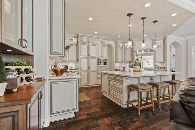 13194 Tierra Heights Rd, Redding, CA 96003 - kitchen with arched walkways, a kitchen island with sink, a kitchen bar, crown molding, and cream cabinets