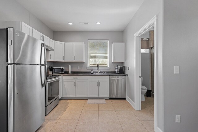 13194 Tierra Heights Rd, Redding, CA 96003 - kitchen featuring white cabinets, dark countertops, under cabinet range hood, stainless steel appliances, and light tile patterned flooring