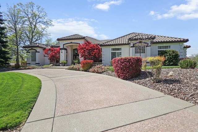13194 Tierra Heights Rd, Redding, CA 96003 - mediterranean / spanish-style home with driveway, a tiled roof, stucco siding, and a front lawn