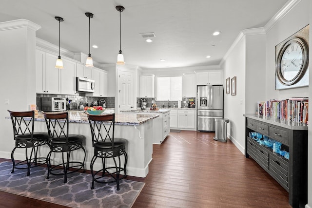 6180 Lucca Trl, Redding, CA 96003 - kitchen with a peninsula, ornamental molding, appliances with stainless steel finishes, dark wood-style flooring, and backsplash