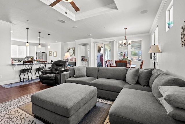 6180 Lucca Trl, Redding, CA 96003 - living area with visible vents, dark wood-style flooring, crown molding, a tray ceiling, and ceiling fan with notable chandelier