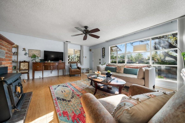 105 Kaer Ave, Red Bluff, CA 96080 - living room featuring light wood-style flooring, a textured ceiling, a wood stove, and a ceiling fan