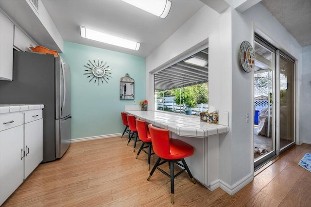 105 Kaer Ave, Red Bluff, CA 96080 - kitchen featuring plenty of natural light, tile countertops, light wood-type flooring, and freestanding refrigerator