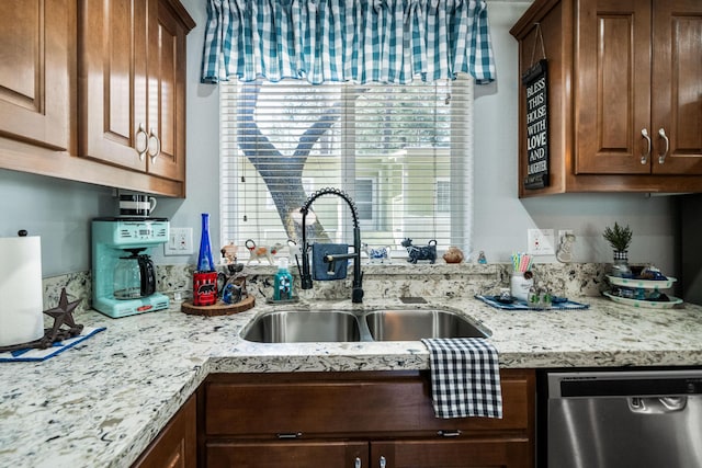 kitchen with a sink, stainless steel dishwasher, and light stone countertops