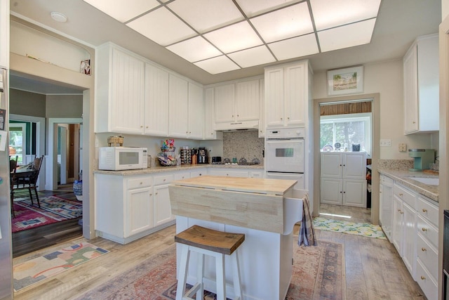 45517 Pittville Rd, Mcarthur, CA 96056 - kitchen featuring white cabinets, a kitchen breakfast bar, white appliances, and light wood-style floors
