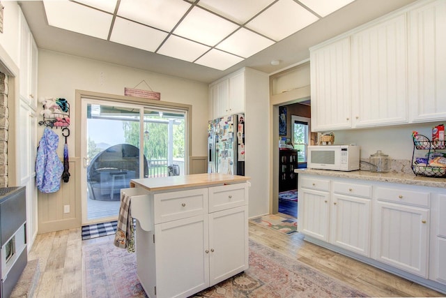 45517 Pittville Rd, Mcarthur, CA 96056 - kitchen featuring light wood-style flooring, white microwave, stainless steel fridge with ice dispenser, and white cabinetry