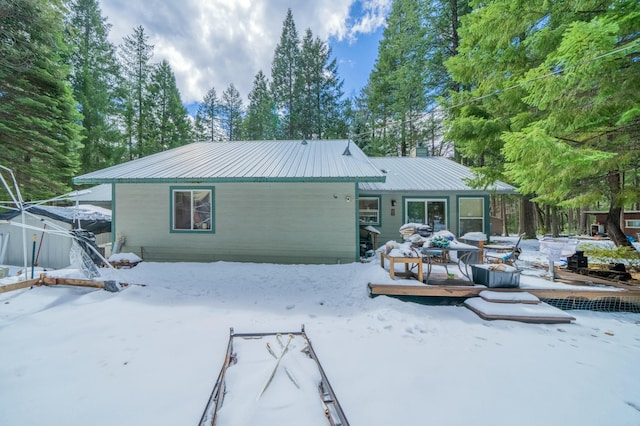 snow covered rear of property featuring a deck and metal roof