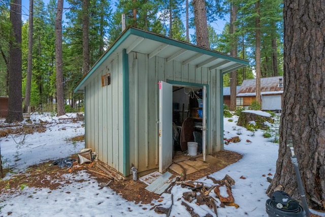 snow covered structure featuring a storage shed and an outbuilding