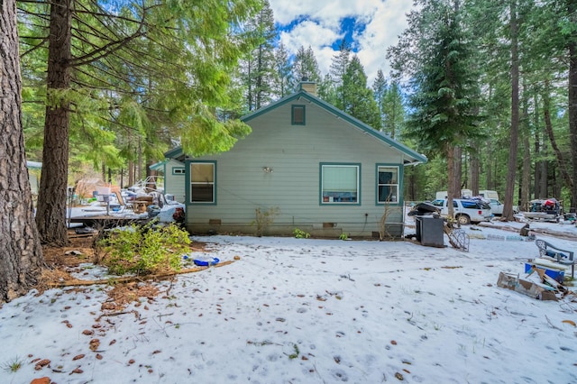 snow covered rear of property with crawl space and a chimney