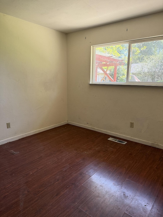 spare room with baseboards, visible vents, and hardwood / wood-style flooring