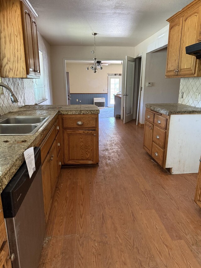 kitchen featuring a sink, a notable chandelier, a peninsula, dishwasher, and wood finished floors
