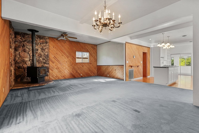 16588 Stanislaus Dr, Redding, CA 96001 - unfurnished living room with wooden walls, beam ceiling, a wood stove, and light colored carpet