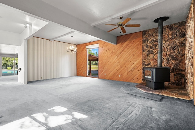 16588 Stanislaus Dr, Redding, CA 96001 - unfurnished living room with carpet flooring, wooden walls, a wood stove, beam ceiling, and ceiling fan with notable chandelier