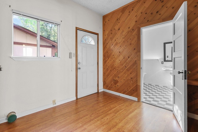16588 Stanislaus Dr, Redding, CA 96001 - entryway with light wood-type flooring, wooden walls, baseboards, and a textured ceiling