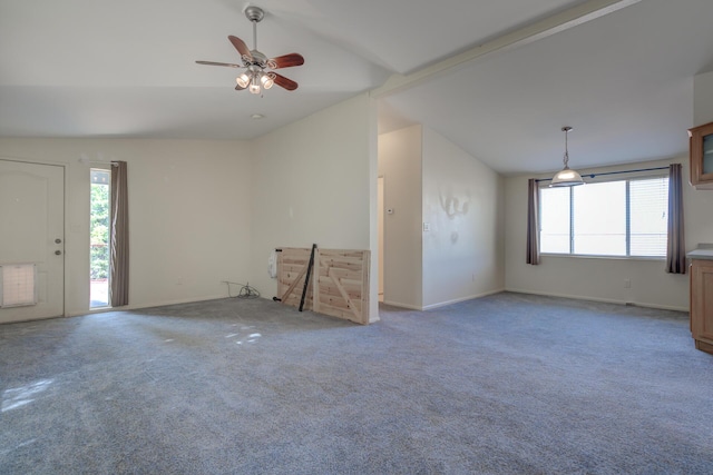 unfurnished living room with ceiling fan, plenty of natural light, vaulted ceiling, and baseboards