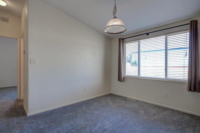 carpeted spare room with visible vents, vaulted ceiling, and baseboards