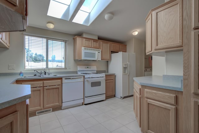 kitchen featuring a sink, visible vents, light brown cabinetry, white appliances, and a skylight