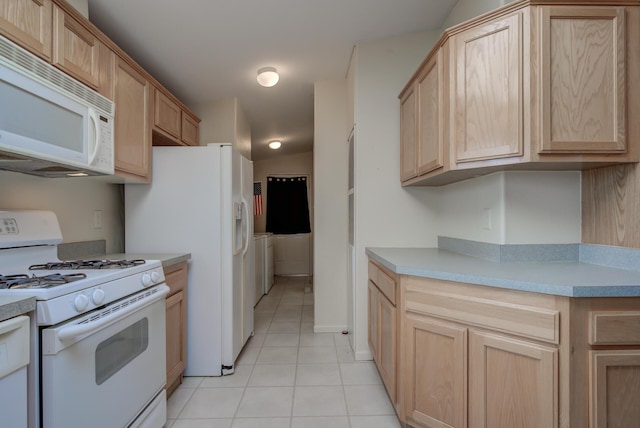 kitchen featuring light tile patterned floors, white appliances, washer / clothes dryer, light brown cabinetry, and light countertops