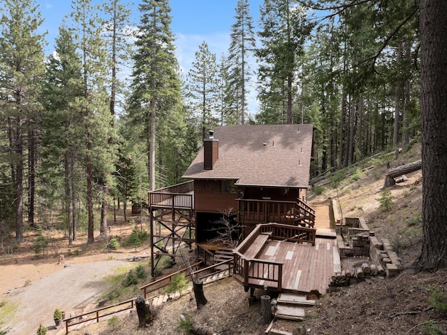 2120 Pack Trl, Mount Shasta, CA 96067 - back of property featuring a forest view, a wooden deck, a shingled roof, and a chimney
