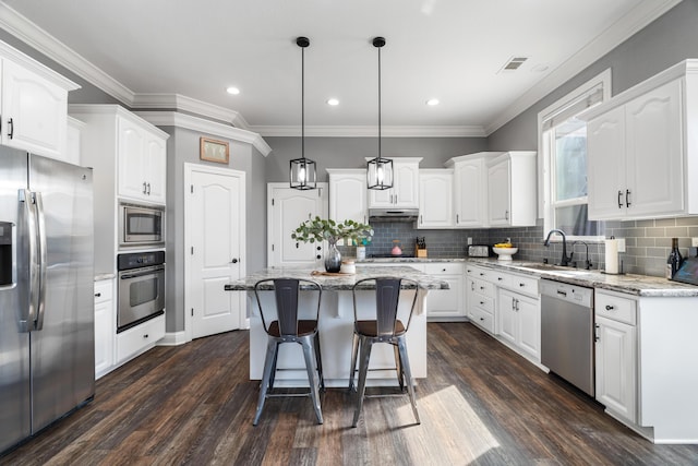 2796 Madison River Dr, Redding, CA 96002 - kitchen with appliances with stainless steel finishes, a kitchen island, white cabinets, and under cabinet range hood