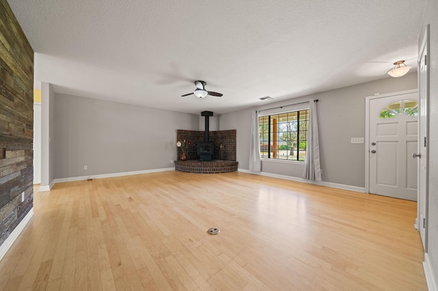19702 Midland Dr, Redding, CA 96003 - unfurnished living room with light wood-style floors, a wood stove, a textured ceiling, a ceiling fan, and baseboards