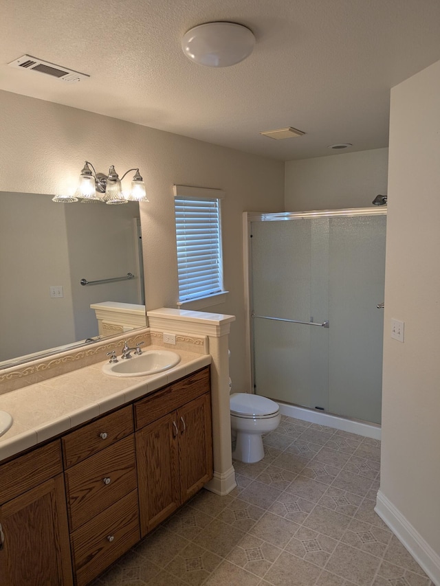 full bathroom with visible vents, a sink, toilet, a shower stall, and double vanity