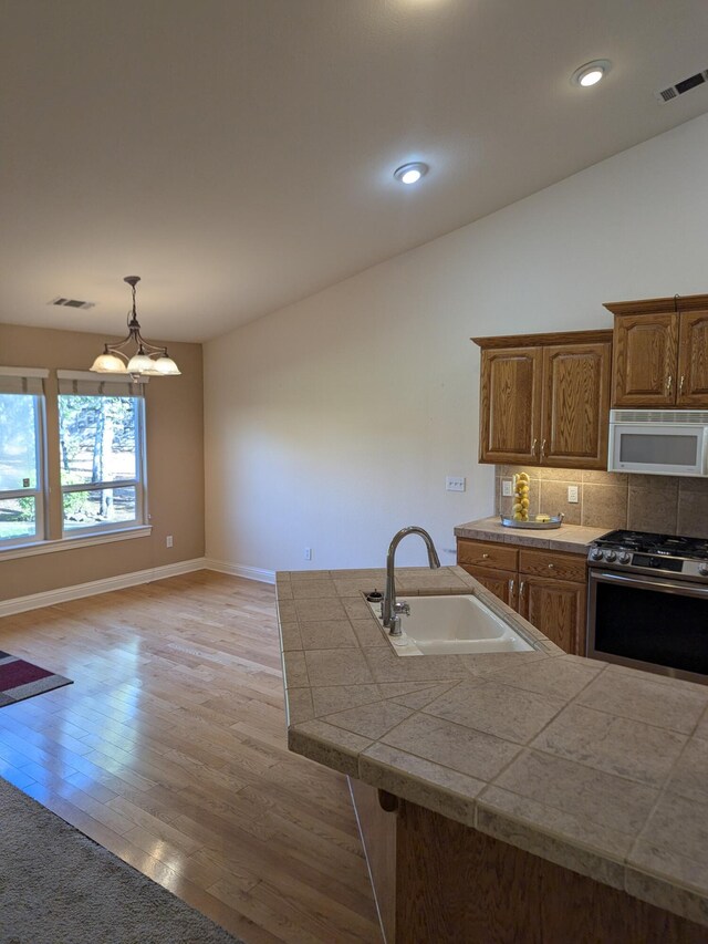 kitchen with visible vents, baseboards, a sink, white microwave, and stainless steel gas stove