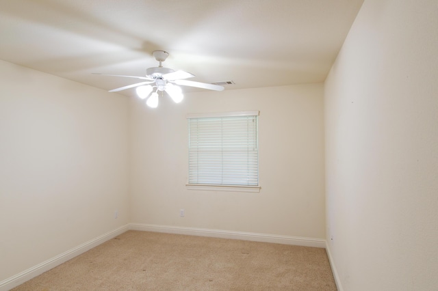empty room featuring light carpet, visible vents, baseboards, and a ceiling fan
