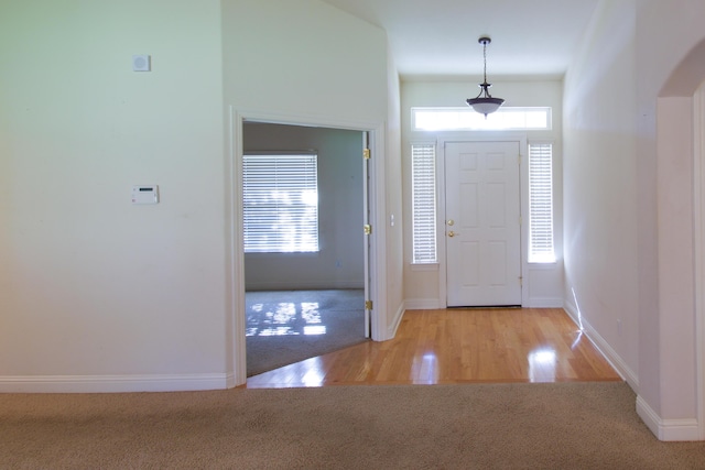 carpeted foyer entrance with baseboards and arched walkways